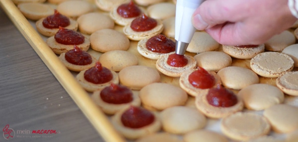 Die Feigenmarmelade wird in die Macarons gespritzt.
